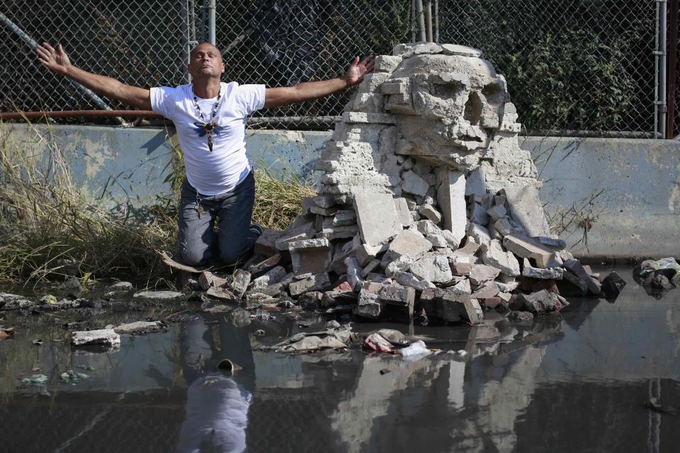 A man poses next to a rock formation by British graffiti artist Banksy is seen in the Queens borough of New York