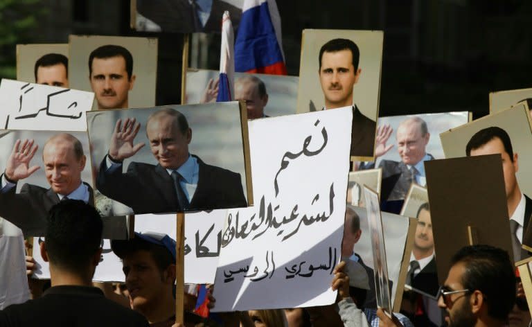 People hold portraits of Syrian President Bashar al-Assad and his Russian counterpart Vladimir Putin (L), outside the Russian embassy in Damascus on October 13, 2015 to show support for Moscow's air war in Syria