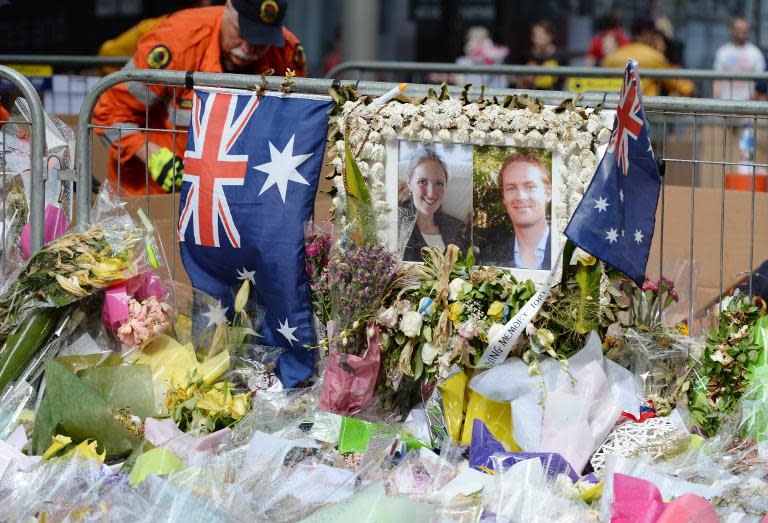 Photos of Katrina Dawson (L) and Tori Johnson are placed outside the Lindt cafe in Sydney on December 23, 2014, a week after a siege at the cafe which saw hostages Dawson and Johnson along with the gunman killed