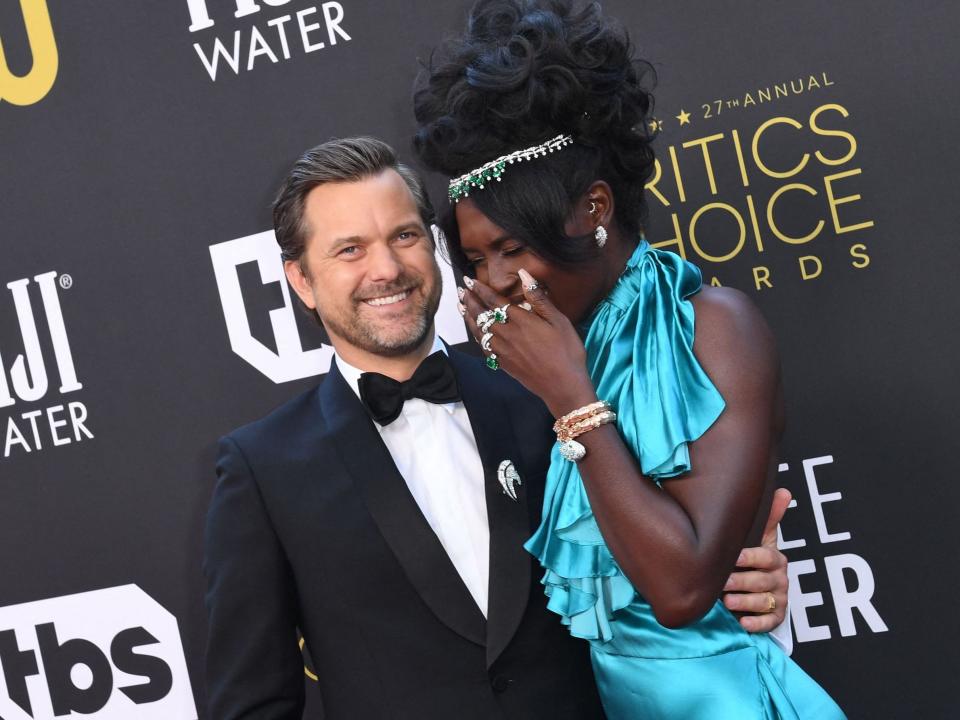 Joshua Jackson and Jodie Turner-Smith laugh together while posing for photos on the red carpet.