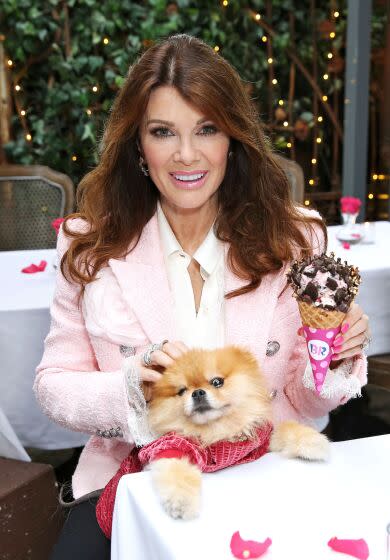 Lisa Vanderpump posing with ice cream cone in hand and dog on her lap, wearing pink blazer