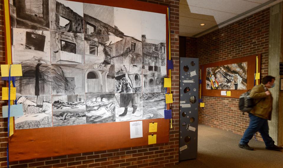 A pair of murals from students portraying the war in Ukraine, draped with comment cards from viewers, stands in the main lobby of the Wilkens Library at Cape Cod Community College, in April.