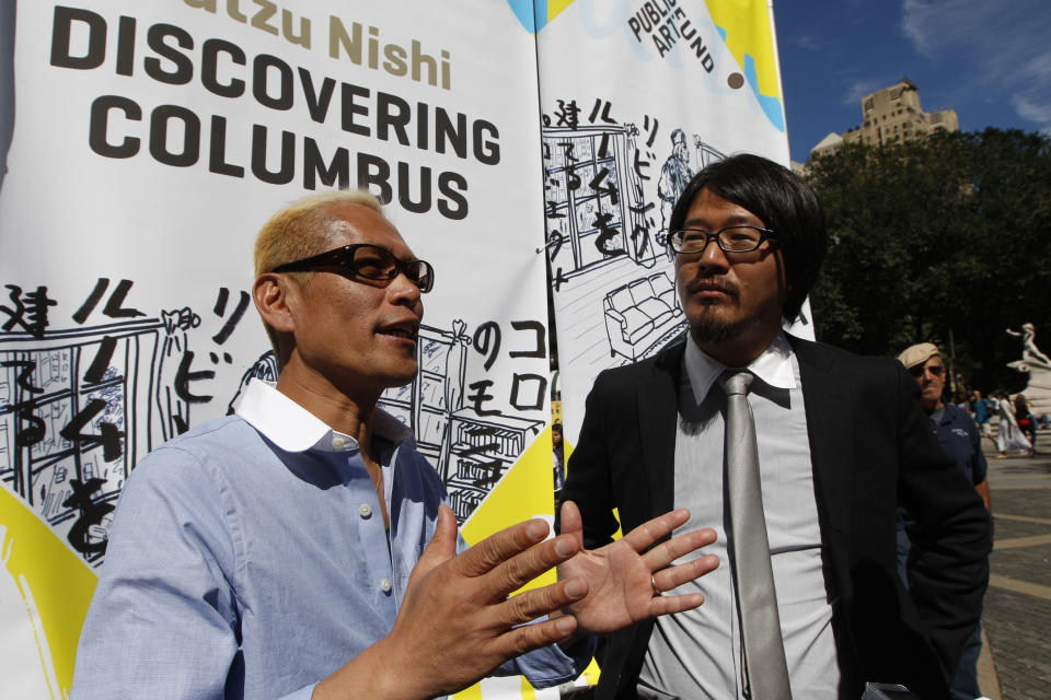 Japanese artist Tatzu Nishi, left, speaks to reporters with the help of translator Kasuke Fujitaka during a media preview of "Discovering Columbus,"  Wednesday, Sept. 19, 2012 in New York.  The 810-square-foot living room offers spectacular views of mid-Manhattan. A 13-foot statue of Christopher Columbus stands amid the couches, lamps and coffee table. (AP Photo/Mary Altaffer)