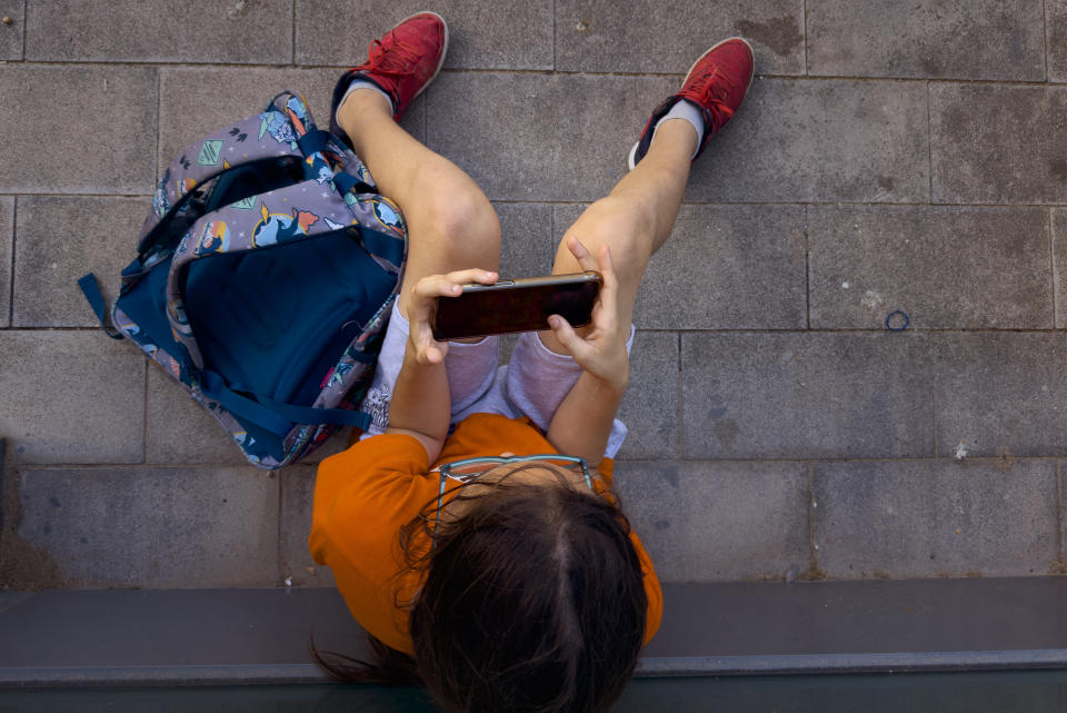 A 11-year-old boy plays with his father's phone outside school in Barcelona, Spain, Monday, June 17, 2024. Parents across Europe are rallying to make it normal for young kids to live smartphone-free. From Spain to Ireland and the UK, groups are ballooning on chat groups like WhatsApp and agreeing to link arms and refuse to buy children younger than 12 smartphones. (AP Photo/Emilio Morenatti)