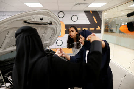 Trainees Maria al-Faraj (C) and Amira Abdelgader check oil level in the engine with their driving instructor (R) during a lesson at Saudi Aramco Driving Center in Dhahran, Saudi Arabia, June 6, 2018. REUTERS/Ahmed Jadallah