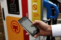 A staff member uses a partner app to pay for his electric car charges at the Holloway Road Shell station where Shell is launching its first fast electric vehicle charging station in London, Britain October 18, 2017. REUTERS/Mary Turner