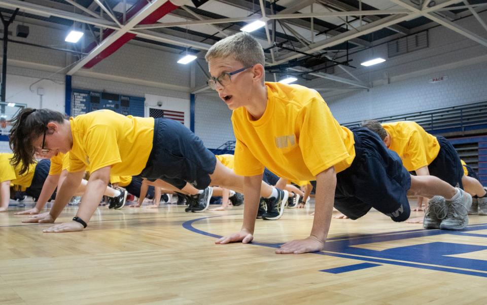 Trevor Young, front, and fellow Navy JROTC cadets exercise during physical training at Pace High School on Friday.