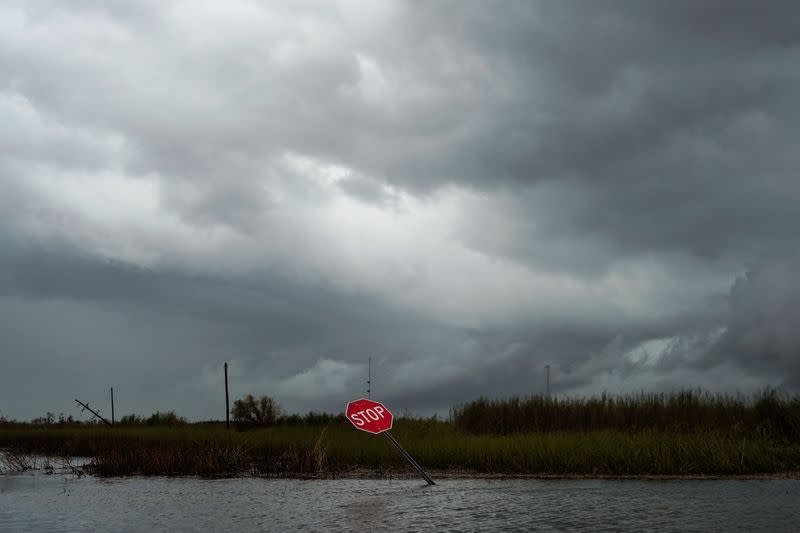 A damaged stop sign and flooding is seen after Hurricane Laura passed through the area in Creole