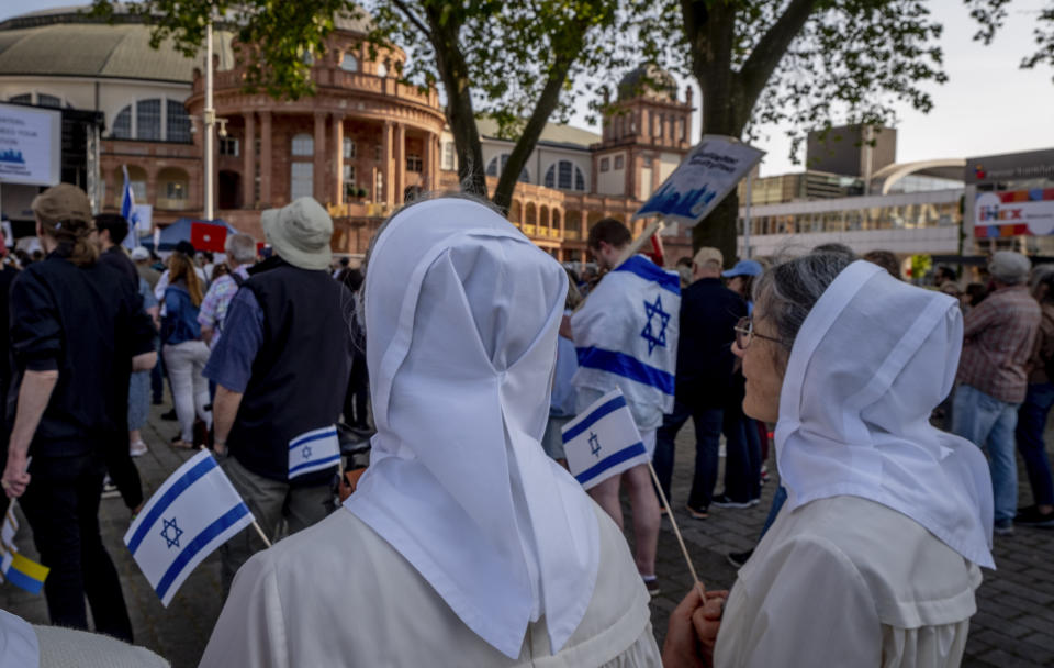 Nuns take part in a demonstration against a concert later the day of former Pink Floyd musician Roger Waters in the Festhalle, background, in Frankfurt, Germany, Sunday, May 28, 2023. The Festhalle was the the place where in the night of broken glasses 1938 about 3000 Jewish men where gathered to deport them to concentration camps. (AP Photo/Michael Probst)