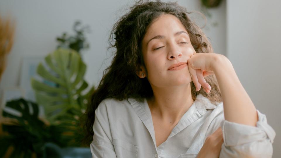 Peaceful and calmness woman with her eyes closed while relaxing sitting on a couch at home.