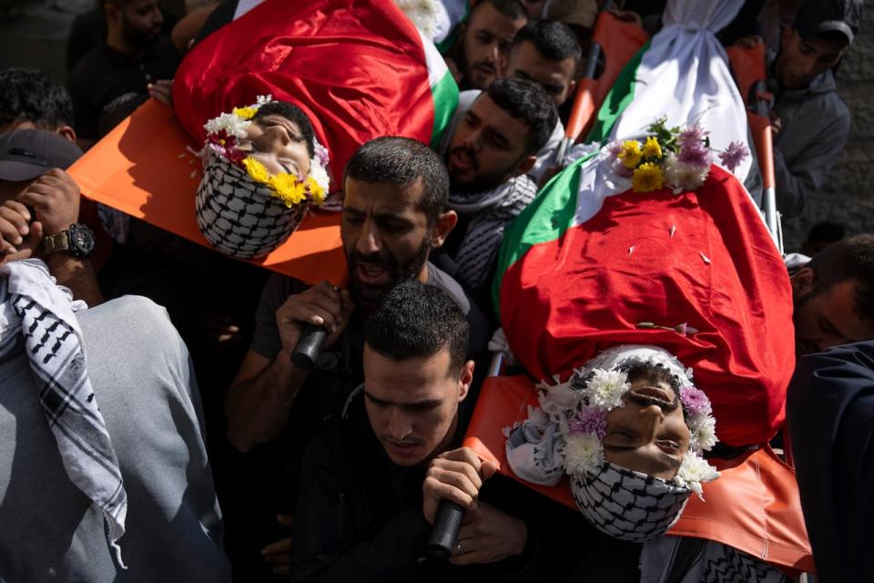 Mourners carry the Bodies of Ibrahim Awad, right, and Mohammad Fawaqa, during their funeral in the West Bank city of Ramallah, Thursday, Oct. 19, 2023. Awad was killed during clashes with Israeli settlers near his home village of Dura al-Qara' and Fawaqa was killed during an Israeli army raid in the village of Qebia, west of Ramallah, while two other Palestinians were killed during Israeli army raids early morning in the occupied West Bank, Palestinian ministry of health said.