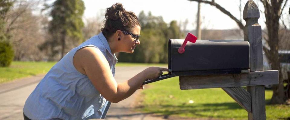 Attractive woman looks inside a mailbox.