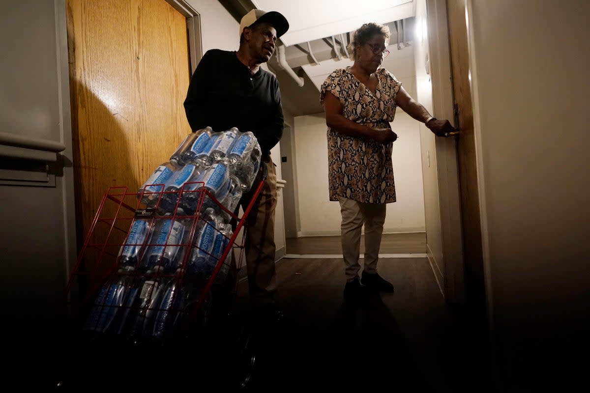 Mary Gaines, right, a resident of the Golden Keys Senior Living apartments, unlocks her door as a friend helps her with cases of fresh water in Jackson (Copyright 2022 The Associated Press. All rights reserved)