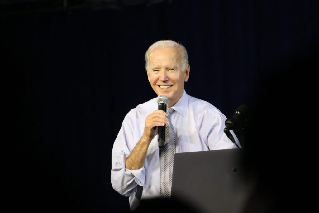 A man in a collared shirt holding a microphone behind a lectern