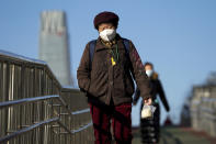 Women wearing face masks to help curb the spread of the coronavirus walk along a pedestrian bridge in Beijing, Monday, Nov. 30, 2020. (AP Photo/Andy Wong)