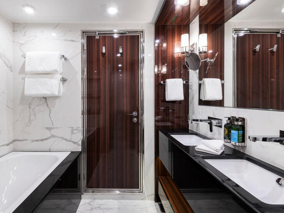 a bath tub, dual sinks, mirrors, and other bathroom amenities