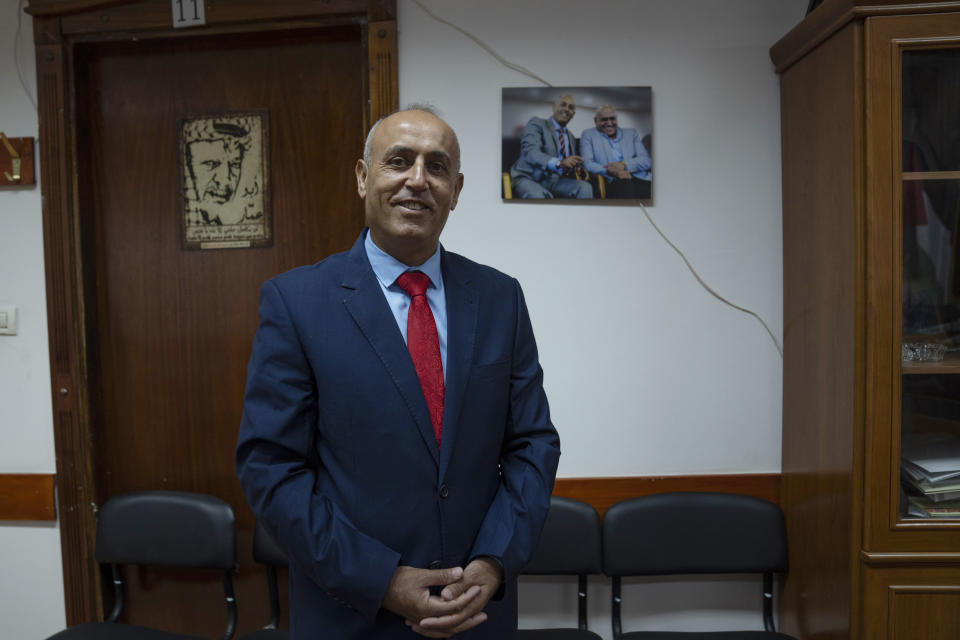 Kamal Abu al-Rub poses for a picture after he was officially named Jenin's acting governor following Palestinian President Mahmoud Abbas' surprise decree retiring governor Akram Rajoub among others, with a picture of both officials in the background, at his office in the occupied West Bank city of Jenin, Sunday, Aug. 13, 2023. (AP Photo/Nasser Nasser)