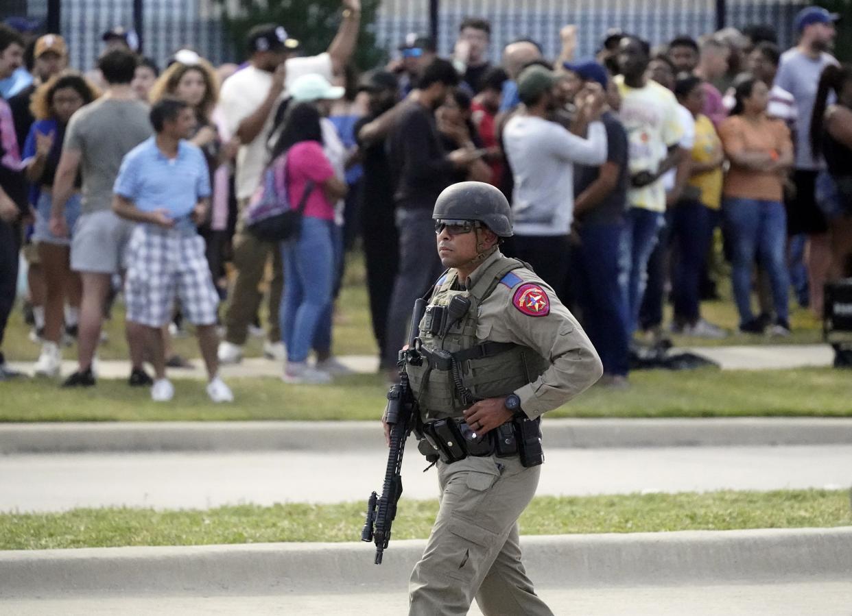 A law enforcement officer walks as people are evacuated from a shopping center where a shooting occurred Saturday, May 6, 2023, in Allen, Texas.  (LM Otero / AP)