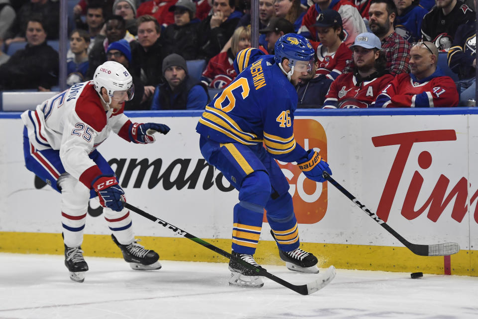 Buffalo Sabres defenseman Ilya Lyubushkin, right, reaches for the puck in front of Montreal Canadiens right wing Denis Gurianov during the first period of an NHL hockey game in Buffalo, N.Y., Monday, March 27, 2023. (AP Photo/Adrian Kraus)
