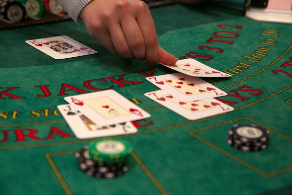 A dealer placing a playing card on a green gambling table