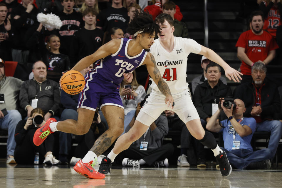 TCU's Micah Peavy, left, dribbles the ball as Cincinnati's Simas Lukosius defends during the first half of an NCAA college basketball game Tuesday, Jan. 16, 2024, in Cincinnati. (AP Photo/Jay LaPrete)