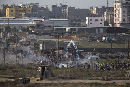 Palestinian protesters throw back a tear gas canister that was fired towards them by Israeli soldiers during clashes over the border fence between Israel and Gaza, October 23, 2015. REUTERS/ Amir Cohen