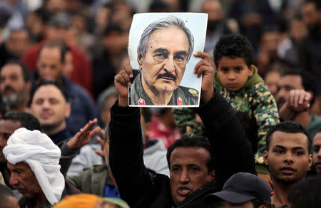 FILE PHOTO: A man holds a poster of Eastern Libyan military commander Khalifa Haftar during a rally demanding Haftar to take over, after a U.N. deal for a political solution missed what his supporters said was a self-imposed deadline on Sunday, in Benghazi, Libya December 17, 2017. REUTERS/Esam Omran Al-Fetori/File Photo