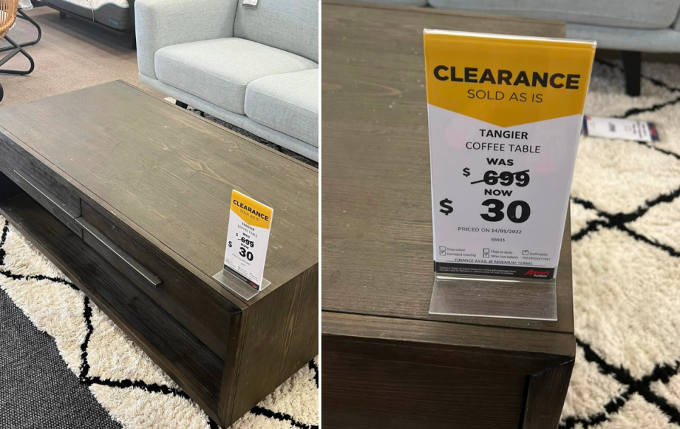 A brown wood coffee table with a clearance sign at Super Amart furniture store