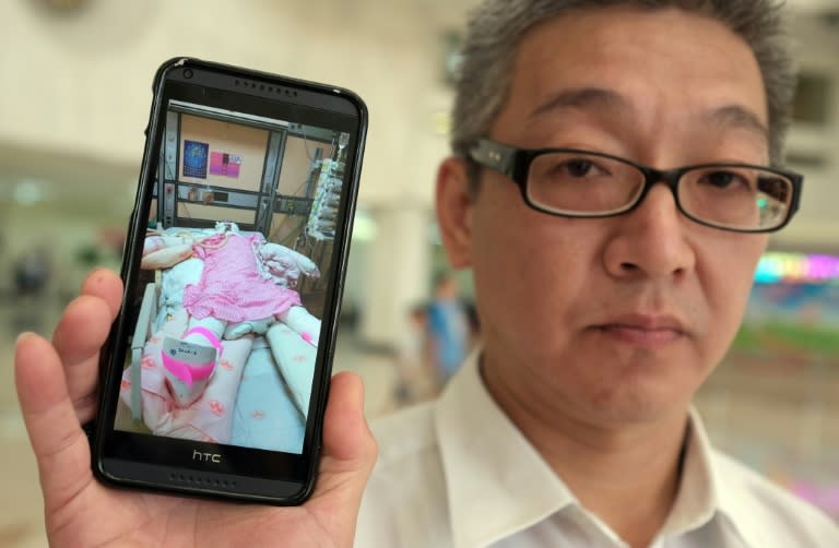 Michael Chu displays an image of his 18-year-old daughter Julie, who suffered burns to more than 70% of her body when a fireball scorched through the crowd at a water park last month, at a Taipei hospital on July 14, 2015
