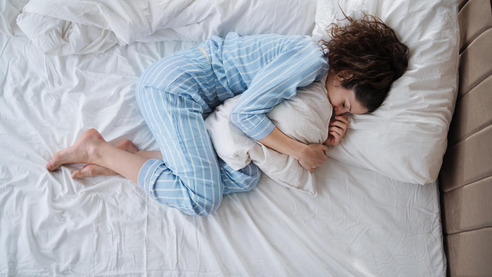 Woman lying in bed hugging pillow. Source: Getty Images