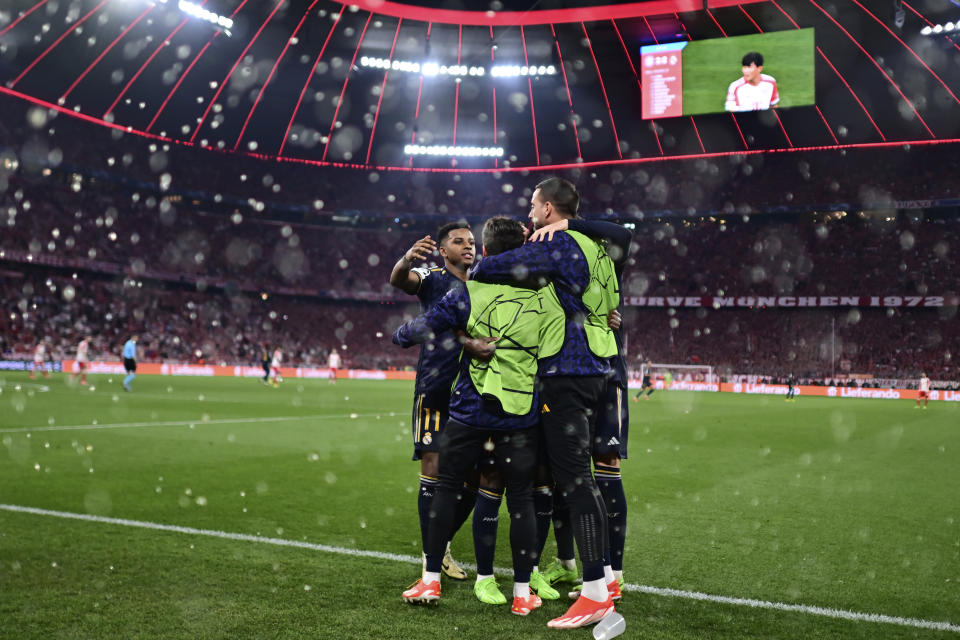 Real Madrid's Vinicius Junior, covered by his teammates, celebrates after scoring his side's second goal on a penalty kick during the Champions League semifinal first leg soccer match between Bayern Munich and Real Madrid at the Allianz Arena in Munich, Germany, Tuesday, April 30, 2024. (AP Photo/Christian Bruna)