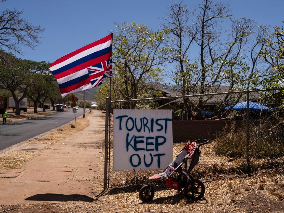 A sign that says "Tourist Keep Out" next to a Hawaiian flag hanging upside down in Lahaina, Hawaii, on August 17, 2023.