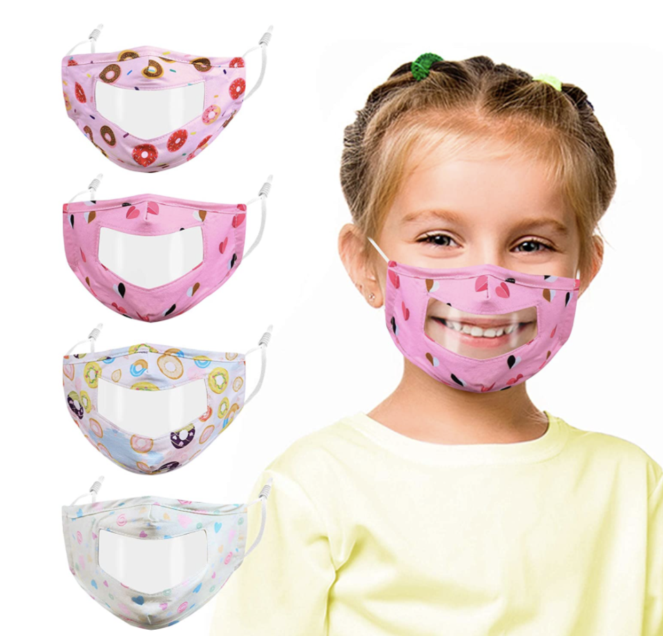 blonde little girl smiling wearing a clear and pink face mask for back to school