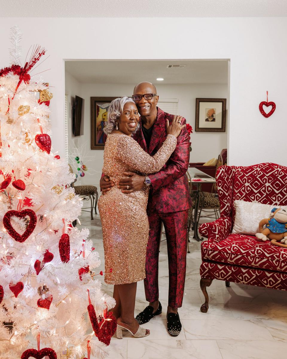 Rita and Theodore embracing in their home and looking at the camera.