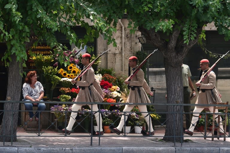 Greek presidential guards march past a flower stand in central Athens, on July 6, 2015