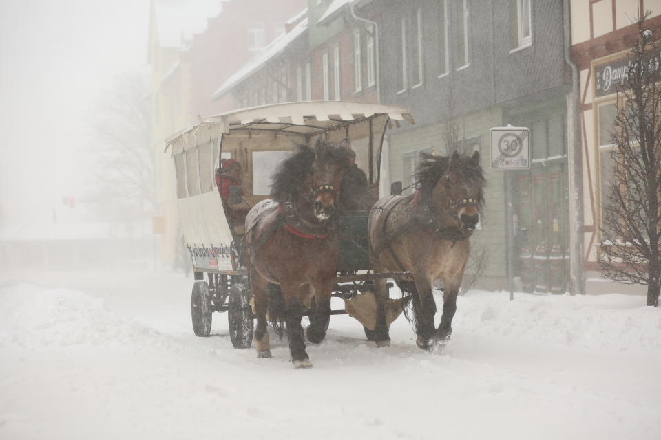 A horse-drawn carriage drives through the town in the snow flurry in Wernigerode, Germany, Sunday, Feb. 7, 2021. Low Tristan has caused huge amounts of snow in the Harz mountains, like here in Wernigerode. (Matthias Bein/dpa via AP)