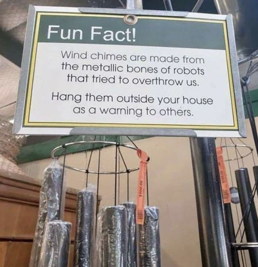 A sign above wind chimes humorously states they are made from the metallic bones of robots who tried to overthrow humans and suggests hanging them as a warning