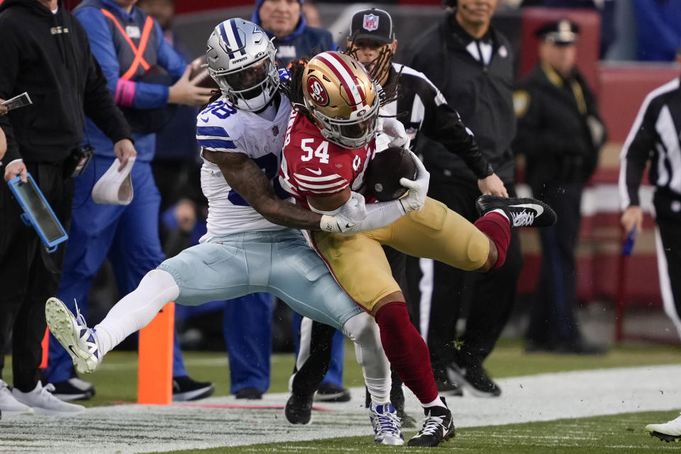 San Francisco 49ers linebacker Fred Warner (54) is tackled by Dallas Cowboys wide receiver CeeDee Lamb after intercepting a pass during the first half of an NFL divisional round playoff football game in Santa Clara, Calif., Sunday, Jan. 22, 2023. (AP Photo/Tony Avelar)
