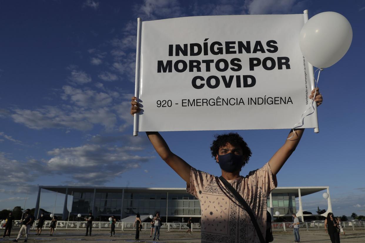 A demonstrator shows a sign with text written in Portuguese that reads "Indians Killed by Covid" during a protest against the lack of action to combat the new coronavirus by the administration of Brazil's President Jair Bolsonaro, in front of the presidential palace, in Brasilia, Brazil, Thursday, Jan. 21. 