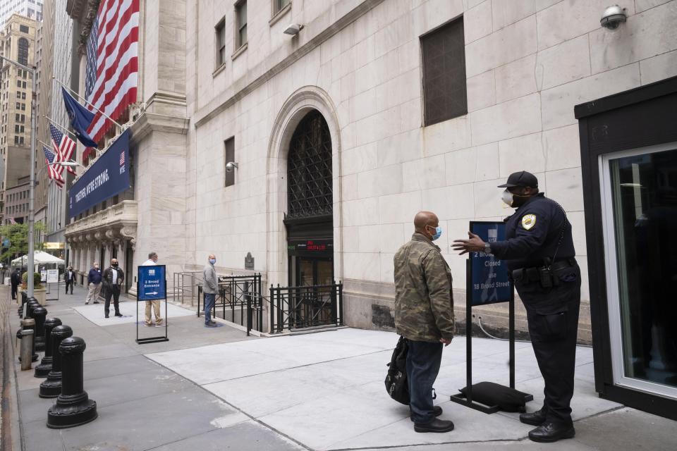 New York Stock Exchange employees wait to enter the building as the trading floor partially reopens, Tuesday, May 26, 2020. (AP Photo/Mark Lennihan)
