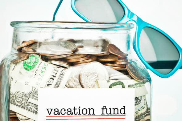 Sunglasses and money jar filled with savings for vacation.