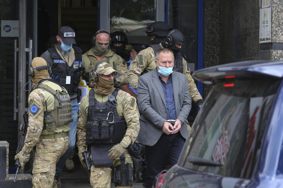 Hysni Gucati, the head of the War Veterans Organization of the Kosovo Liberation Army is escorted by European Union security police officers, from the offices of a war veterans association in Kosovo, in Pristina, Friday, Sept. 25, 2020. Witnesses say European Union security police have stormed the offices of a war veterans association in Kosovo. The association represents the former ethnic Albanian separatists who fought Serbian troops in a 1998-1999 war for independence. Members of the group said police from the European Union Rule of Law Mission in Kosovo, or EULEX, prevented them from going into the association’s offices in Pristina on Friday. (AP Photo/Visar Kryeziu)