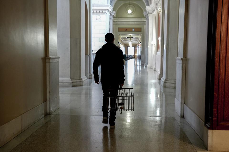 A quahogger carries his bullrake after leaving a State House hearing before a legislative commission that's studying the decline in quahog harvests.