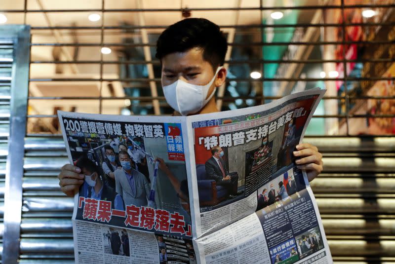 A supporter of Apple Daily newspaper, reads a copy of Apple Daily newspaper to support media mogul Jimmy Lai Chee-ying, founder of Apple Daily after he was arrested by the national security unit, in Hong Kong