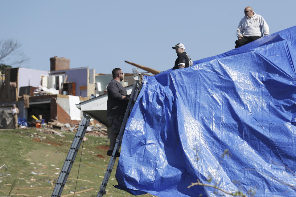 Workers put a tarp over a room of a storm-damaged home Tuesday, April 14, 2020, in Chattanooga, Tenn. Tornadoes went through the area Sunday, April 12. (AP Photo/Mark Humphrey)