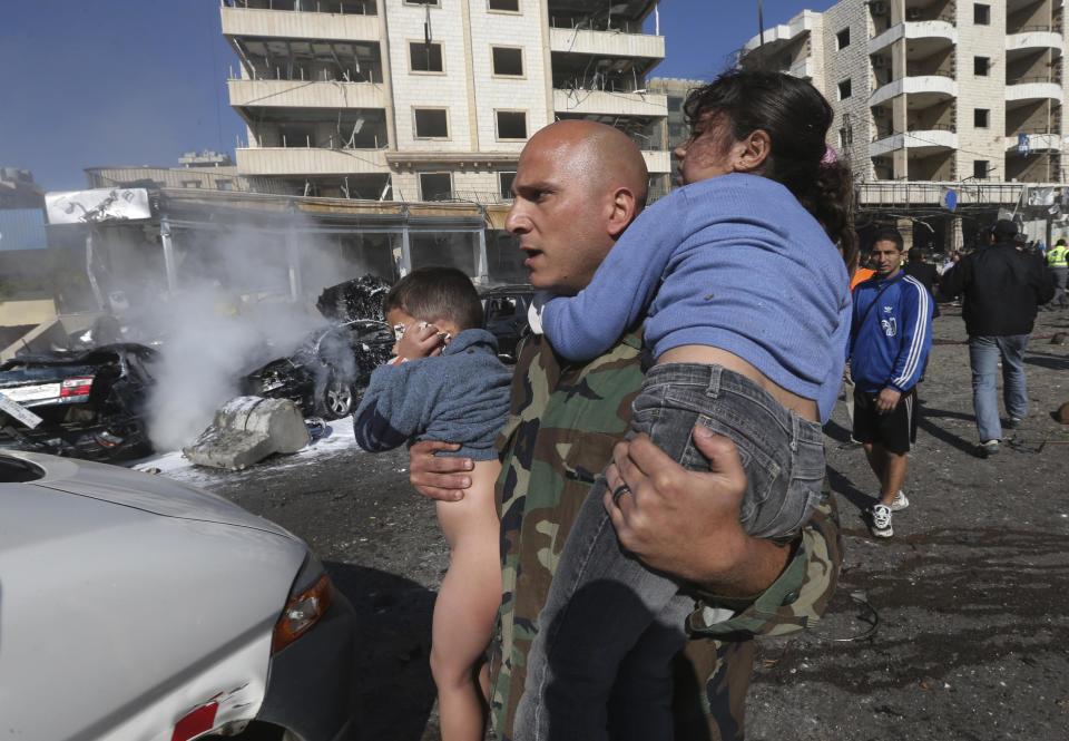 A Lebanese army soldier carries two injured children away from the site of an explosion near the Kuwaiti Embassy and Iran's cultural center, in the suburb of Beir Hassan, Beirut, Lebanon, Wednesday, Feb. 19, 2014. The bombing in a Shiite district in southern Beirut killed several people on Wednesday, security officials said — the latest apparent attack linked to the civil war in neighboring Syria that has killed and wounded scores of people over the last few months. (AP Photo/Hussein Malla)