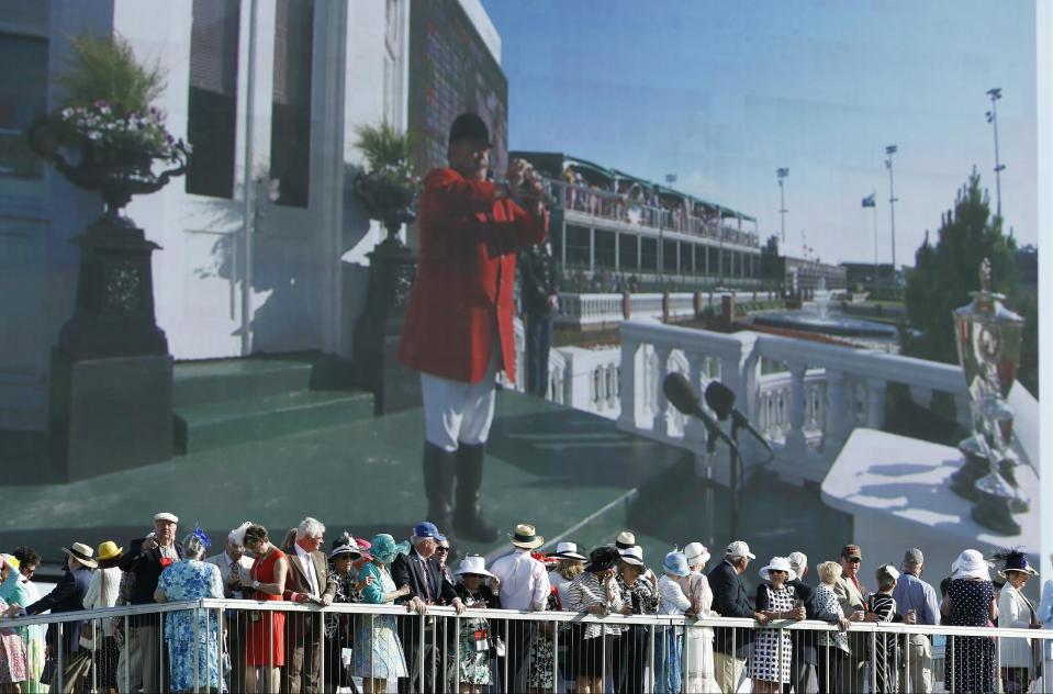 Fans watch the 140th running of the Kentucky Derby horse race at Churchill Downs on a large video screen Saturday, May 3, 2014, in Louisville, Ky. (AP Photo/Matt Slocum)