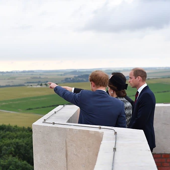 Three people, presumably royalty, look out over a rural landscape from a high vantage point