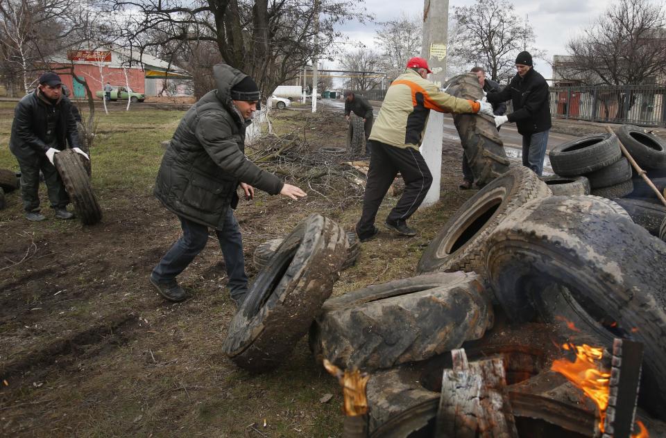 Pro Russian activists block a road with car tires near the armory Ukrainian army to prevent the export of arms and ammunition in the village of Poraskoveyevka, eastern Ukraine, Thursday, March 20, 2014. The disheveled men barricading the muddy lane leading into a military base in this eastern Ukraine village say they're taking a stand to defend Russian-speakers. (AP Photo/Sergei Grits)