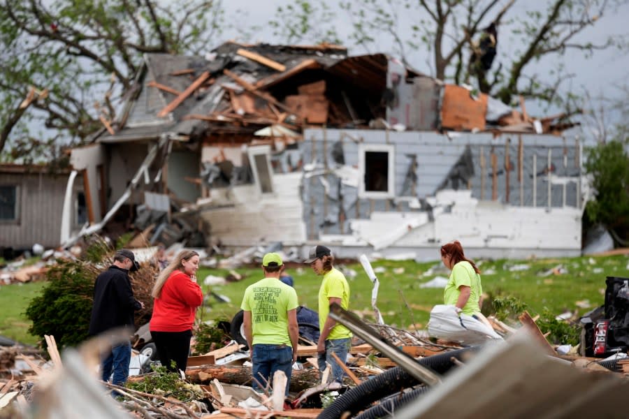 People sort through the remains of a home damaged by a tornado Tuesday, May 21, 2024, in Greenfield, Iowa. (AP Photo/Charlie Neibergall)